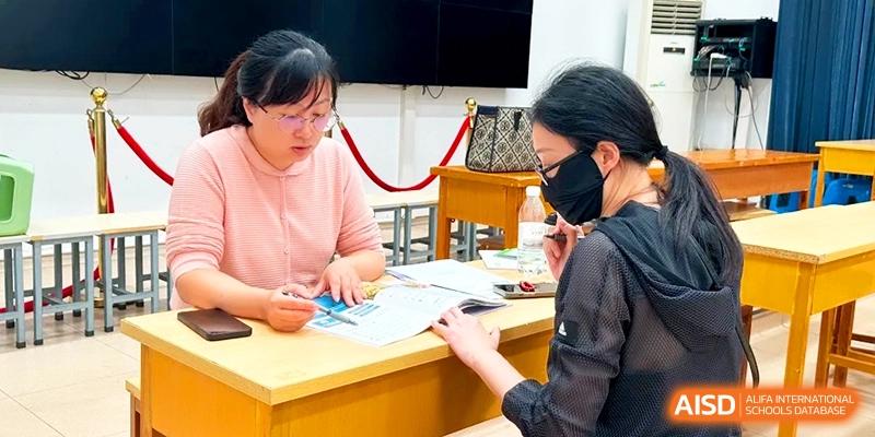 Two female staff members review educational documents together at a desk during a planning session at Xishan Senior High School.