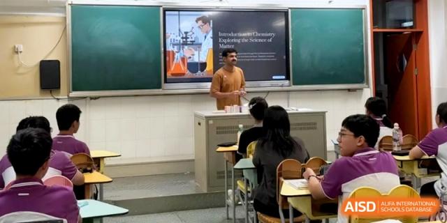 A male teacher stands at a podium in front of a digital screen titled Chemistry of Matter at Xishan Senior High School.