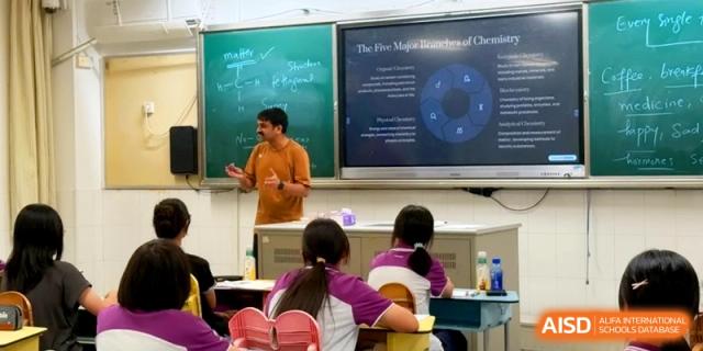 A male educator stands before a digital screen displaying chemistry concepts while teaching a class at Xishan Senior High School.