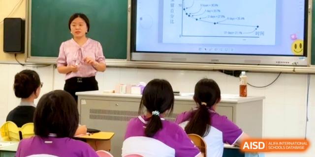 A female teacher explains a graph shown on a large interactive whiteboard to her students at Xishan Senior High School.