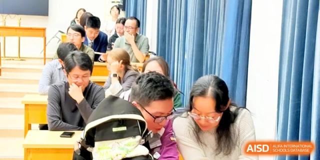 Two students look closely at a notebook while participating in a group activity in a lecture hall at Xishan Senior High School.