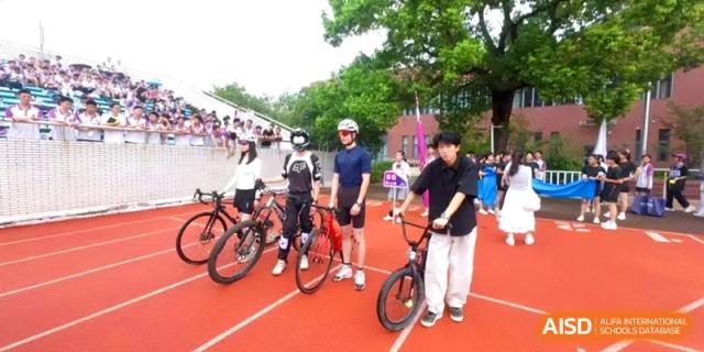 Four students with their bicycles pose on the red running track during an outdoor sports activity at Xishan Senior High School.