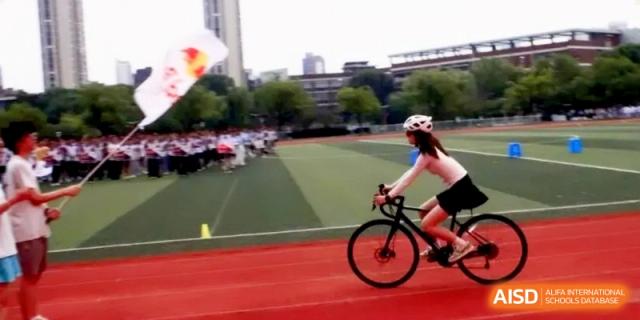 A student athlete rides a bicycle quickly along the running track during a competitive event at Xishan Senior High School.