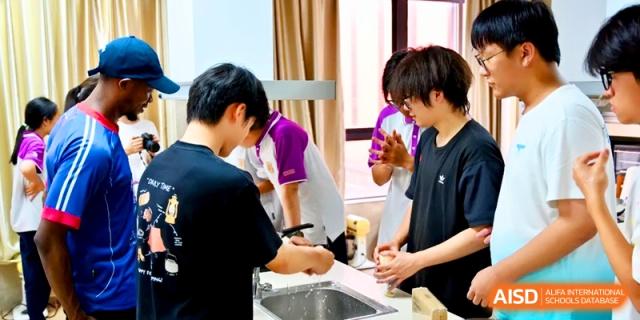 Male students in a modern kitchen lab wash equipment and prepare their workspace for a cooking lesson at Xishan Senior High School.