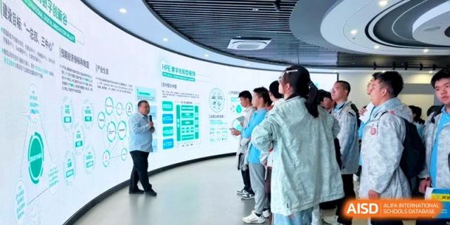 Students listen to a guide explain a large wall display in a modern information center at Kunshan Senior High School.