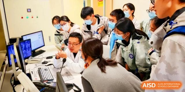 Students gather around a professional in a lab coat to learn about medical or scientific equipment at Kunshan Senior High School.