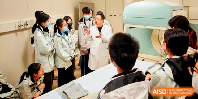 A researcher in a white coat explains scientific concepts to a group of attentive students at Kunshan Senior High School.