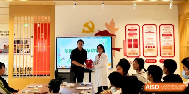Two people stand at the front of a room during a formal gift or award exchange ceremony at Kunshan Senior High School.