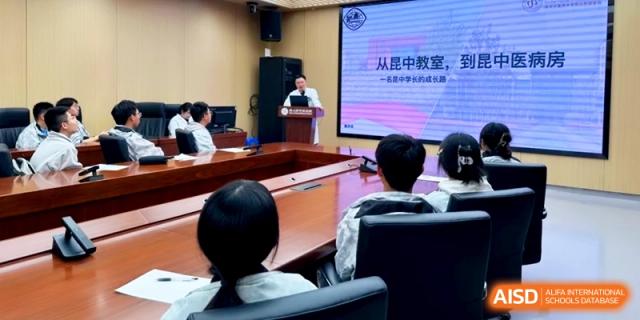 A speaker addresses a room of students from a podium during a formal school assembly at Kunshan Senior High School.