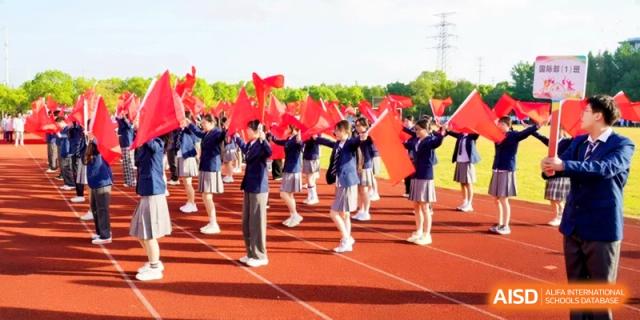 A large group of students wave red flags in a synchronized performance on the track at Kunshan Senior High School.