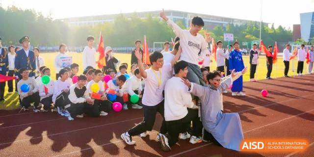 A group of students playfully lift a classmate during a joyful outdoor gathering at Kunshan Senior High School.