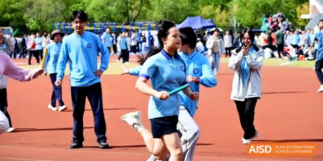 A student runner carries a baton during a relay race on a sunny day at Kunshan Senior High School.