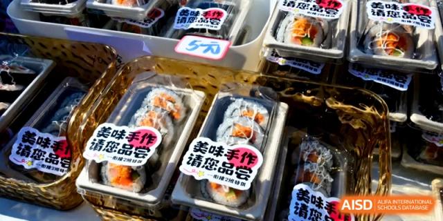 Trays of freshly made sushi rolls are packaged and labeled for sale at an outdoor food stall at Kunshan Senior High School.