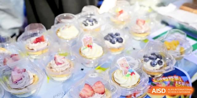 Small dessert cups filled with cream, berries, and decorative toppers are arranged in rows at Kunshan Senior High School.