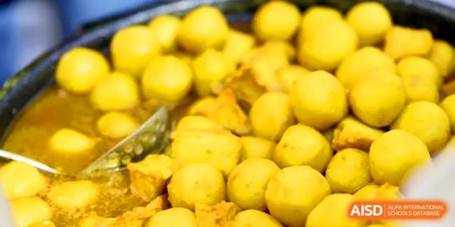 A large container is filled with golden-brown fried fish balls or tofu puffs ready for snacking at Kunshan Senior High School.