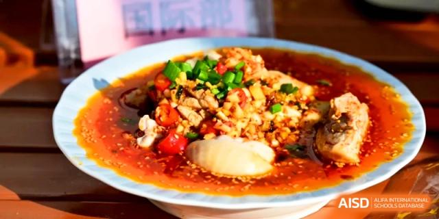 A bowl of silken tofu topped with a savory minced meat sauce, scallions, and red peppers at Kunshan Senior High School.