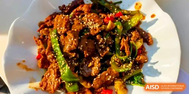 A vibrant stir-fry of sliced beef, green peppers, and onions seasoned with sesame seeds at Kunshan Senior High School.