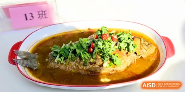 A whole steamed fish topped with a generous amount of fresh cilantro and chili peppers at Kunshan Senior High School.