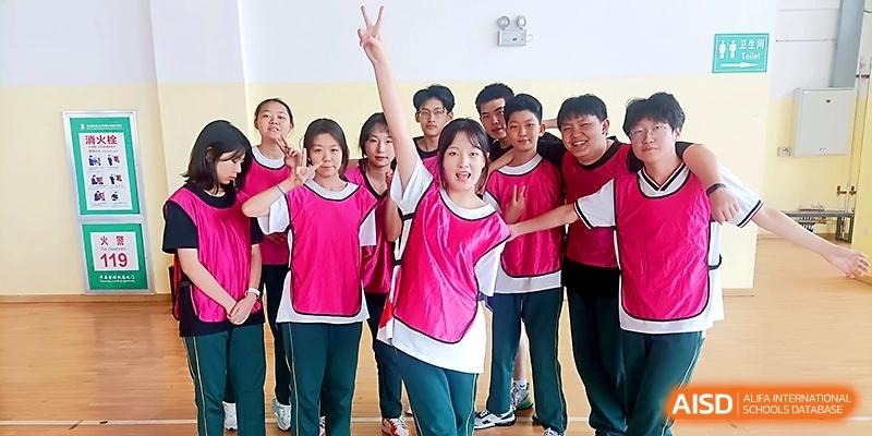 A cheerful group of students in pink and green athletic jerseys pose for a team photo at Maple Leaf International School - Xi_an.