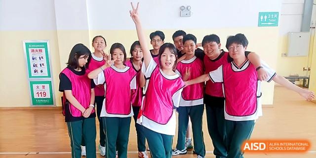 A cheerful group of students in pink and green athletic jerseys pose for a team photo at Maple Leaf International School - Xi_an.