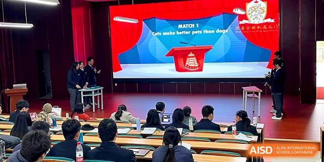 Students sit in a lecture hall watching a presentation titled Cats make better pets than dogs at Maple Leaf International School - Xi_an.