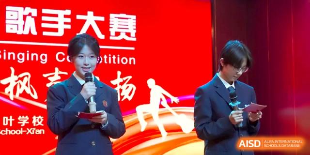 A student speaking into a microphone in front of a red competition backdrop at Maple Leaf International School - Xi_an.