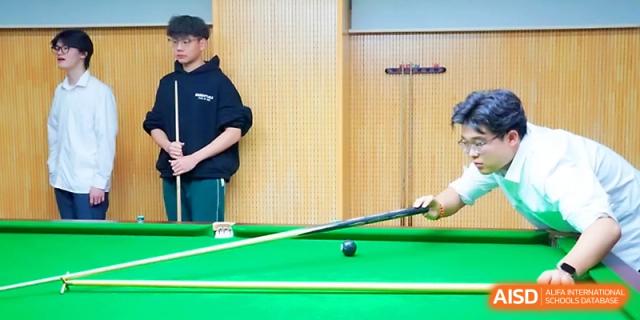 A student athlete preparing a shot on a green billiards table at Maple Leaf International School - Xi_an.