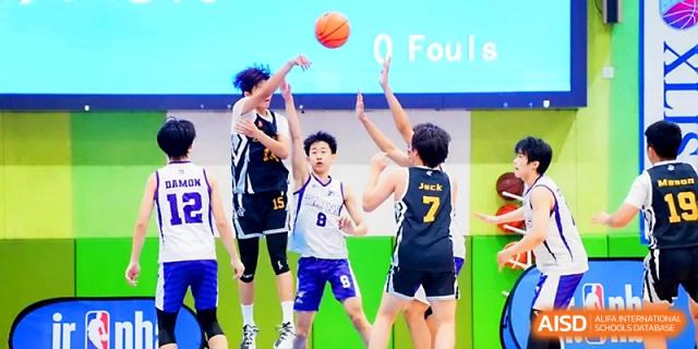 Students jumping for a tip-off during a basketball game in the gym at Maple Leaf International School - Xi_an.