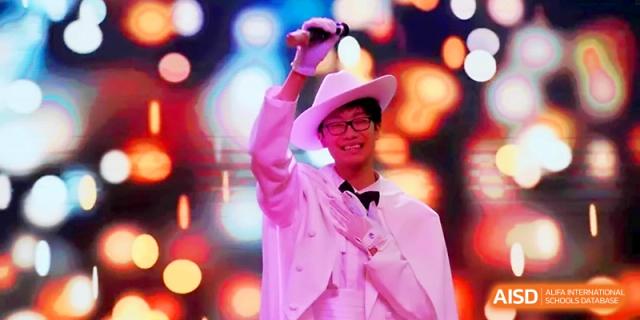 A student in a white suit and hat performing under bright stage lights at Maple Leaf International School - Xi_an.