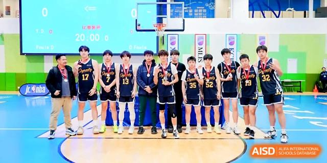 A boys' basketball team in black and yellow uniforms posing on the court at Maple Leaf International School - Xi_an.