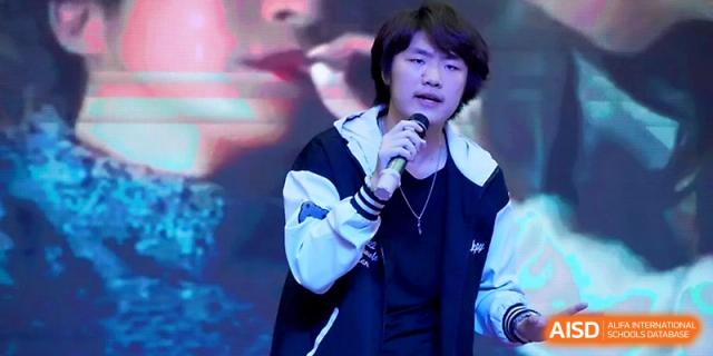 A male student singing into a microphone during a talent show at Maple Leaf International School - Xi_an.