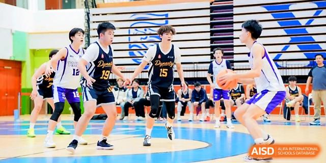 Two basketball players in black uniforms during an active game on the court at Maple Leaf International School - Xi_an.