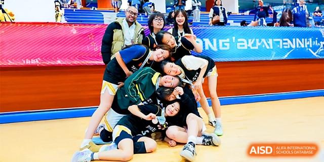 A group of female athletes in green jerseys posing and smiling together at Maple Leaf International School - Xi_an.