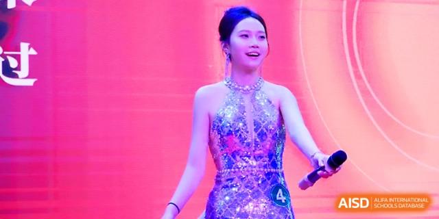 A female student in a sparkling silver dress performing on a bright stage at Maple Leaf International School - Xi_an.