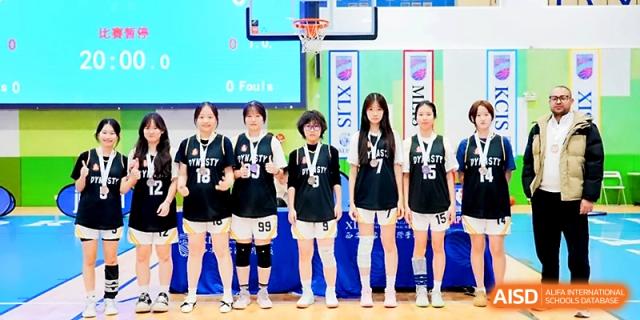 A girls' basketball team in black uniforms standing in a line on the court at Maple Leaf International School - Xi_an.