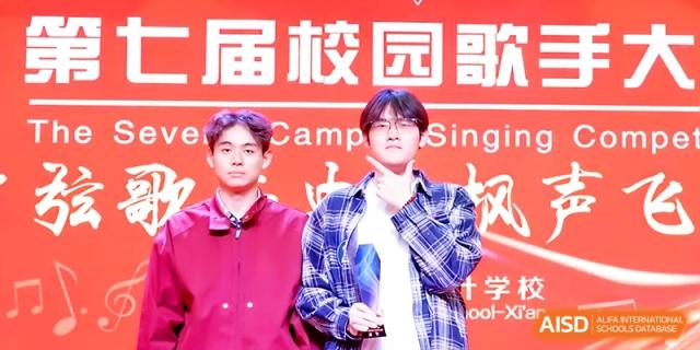Two male students standing in front of a red "Campus Singing" banner at Maple Leaf International School - Xi_an.