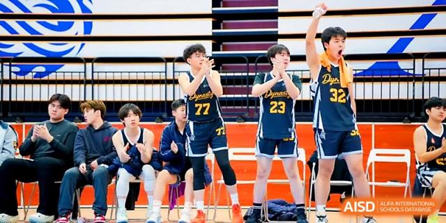 Basketball players in blue and yellow uniforms sitting on the sidelines at Maple Leaf International School - Xi_an.