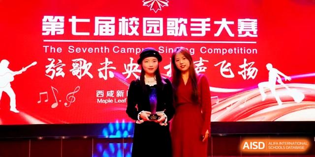A student and teacher posing with an award in front of a red backdrop at Maple Leaf International School - Xi_an.