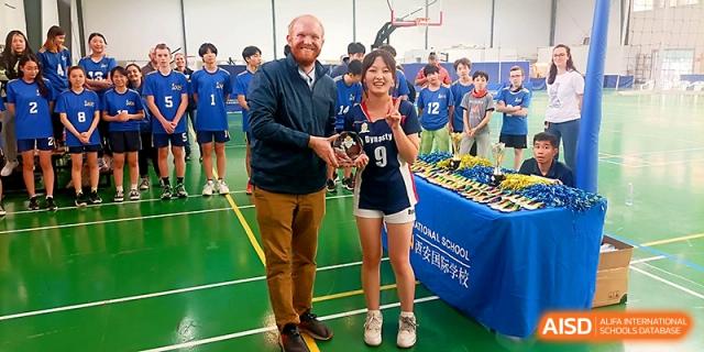 A teacher presenting an award to a student athlete on the court at Maple Leaf International School - Xi_an.