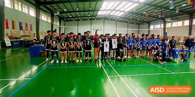 A large group of students in athletic gear posing in an indoor sports hall at Maple Leaf International School - Xi_an.