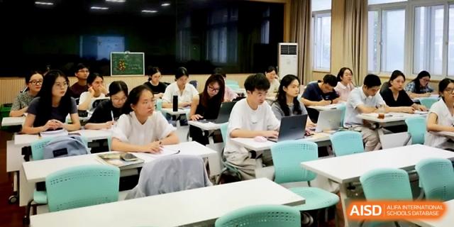 Teachers and staff participate in a collaborative workshop using laptops and physical documents at Ningbo Beilun High School.