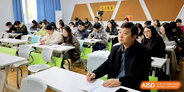 An educator in a suit listens intently during a professional teaching seminar in a bright classroom at Ningbo Beilun High School.