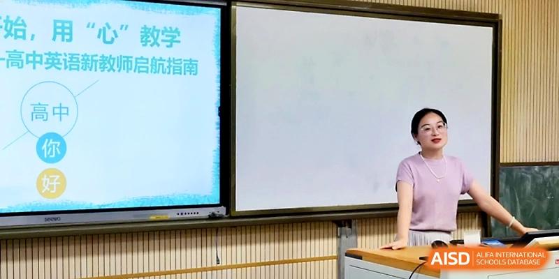 A teacher uses a large touchscreen display to show educational slides to an attentive classroom at Ningbo Beilun High School.