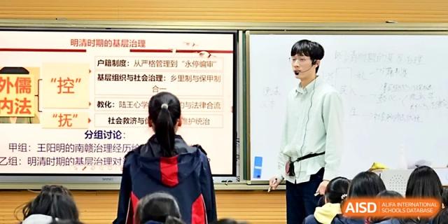 A male educator wearing a microphone leads a discussion on social studies and governance at Ningbo Beilun High School.