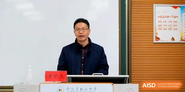 A male speaker addresses a large audience from a podium during a formal school event or ceremony at Ningbo Beilun High School.