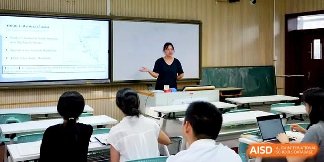 A teacher stands at the front of a classroom explaining a geometry lesson on a digital whiteboard at Ningbo Beilun High School.