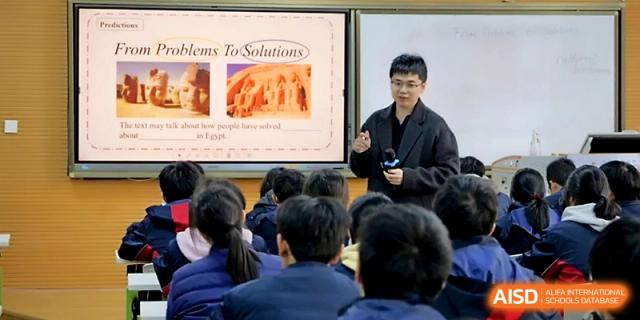 A teacher presents a "Problems To Solutions" slide during a critical thinking workshop for students at Ningbo Beilun High School.