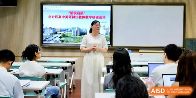 A teacher in a white dress leads a lecture with a digital presentation on the screen for students at Ningbo Beilun High School.