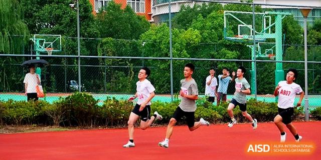 Two male athletes maintain a steady pace during a long-distance race on the school track at Ningbo Beilun High School.