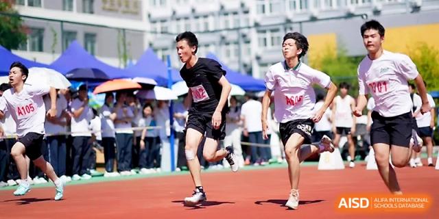 Two male runners sprint toward the finish line during a competitive track meet at Ningbo Beilun High School.